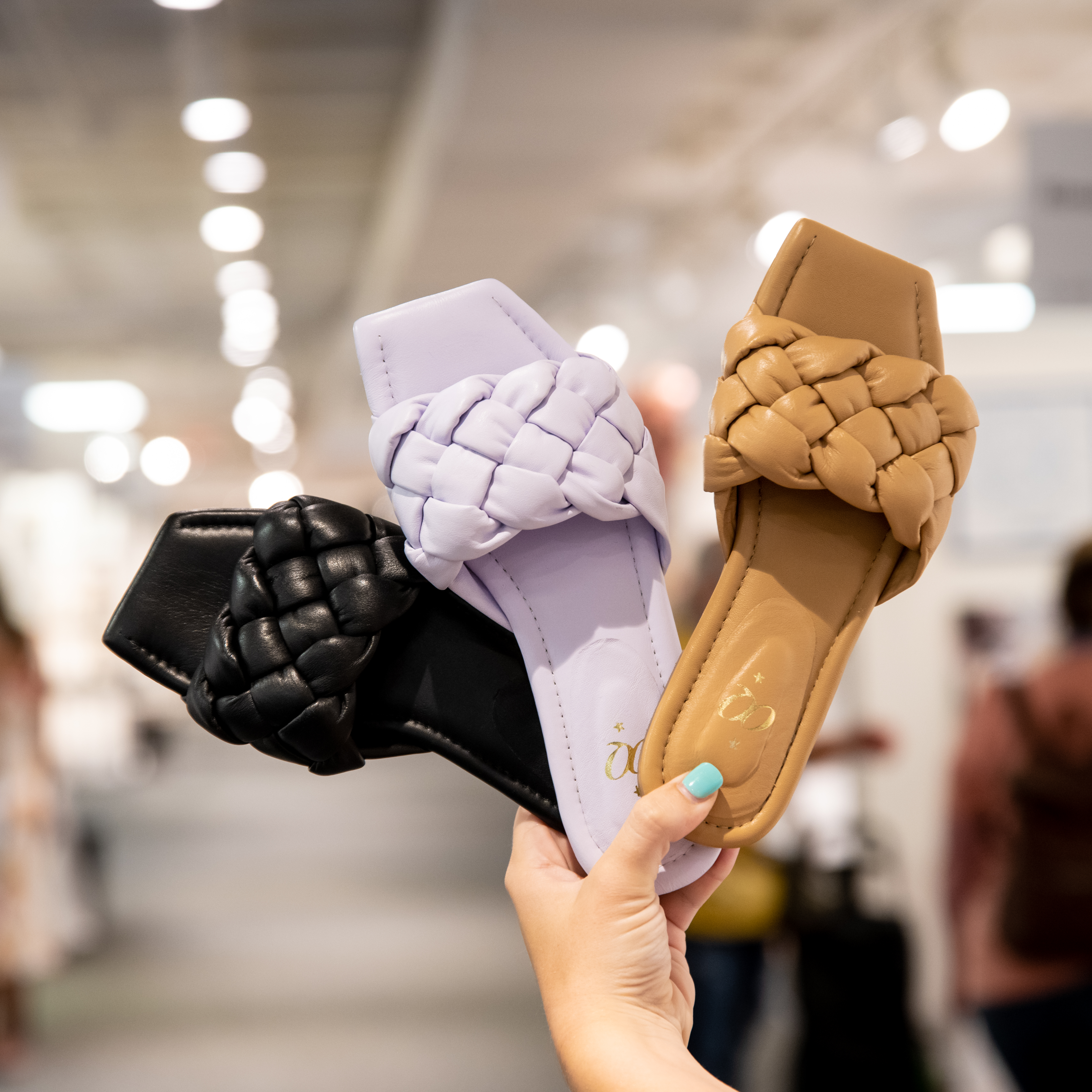 3 sandals (black, purple, and tan) being held